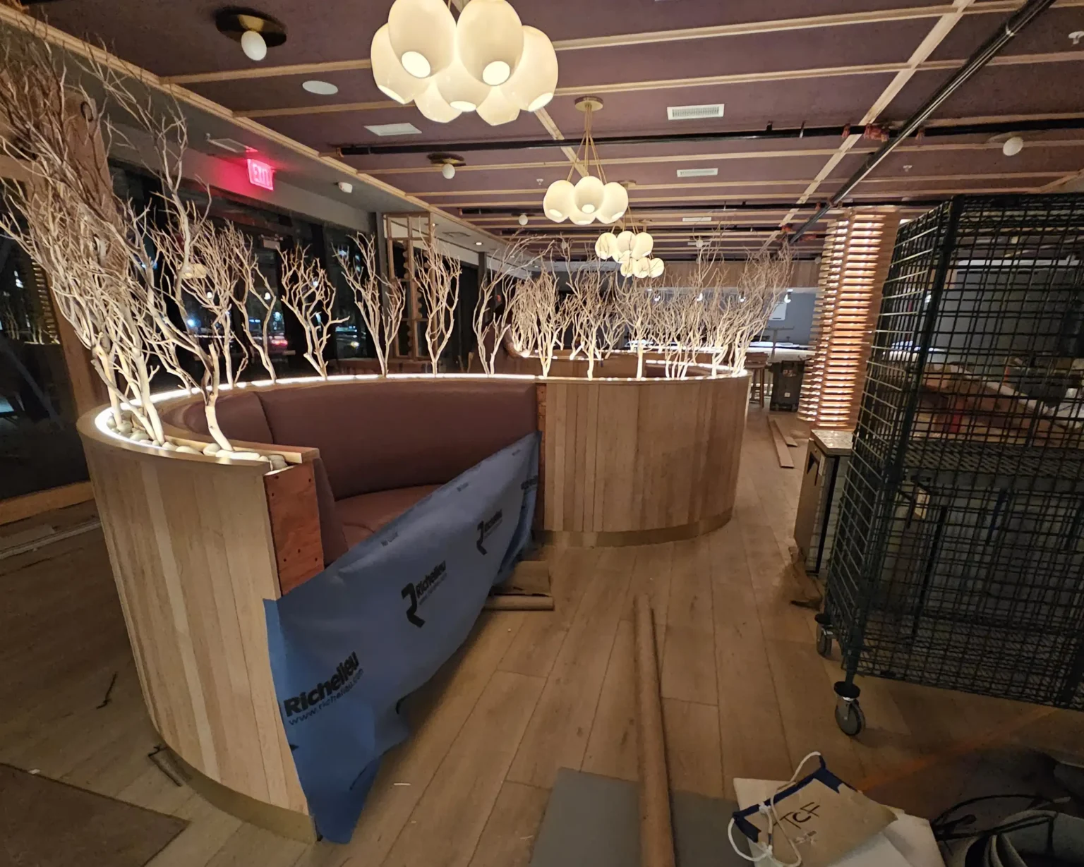 Close-up of sandblasted manzanita branches used as decorative booth dividers with soft lighting in upscale restaurant interior design